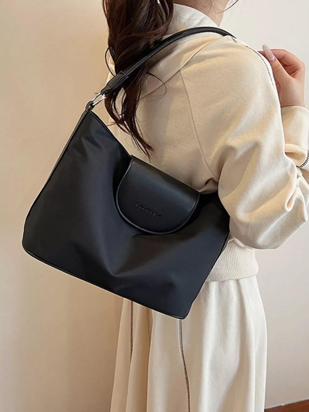 Black canvas hobo crossbody bag with a flap closure and adjustable strap.