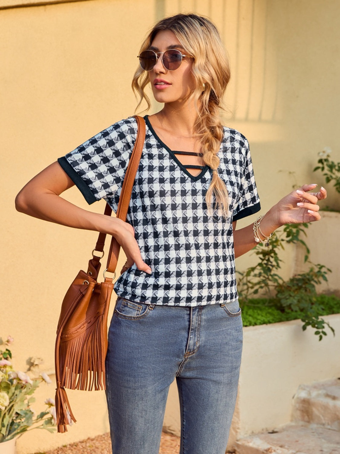 Houndstooth tunic top with cutout neckline and short sleeves, styled with jeans.