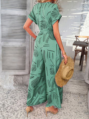 Geometric print wide-leg jumpsuit in Gum Leaf with short sleeves and a belted waist.