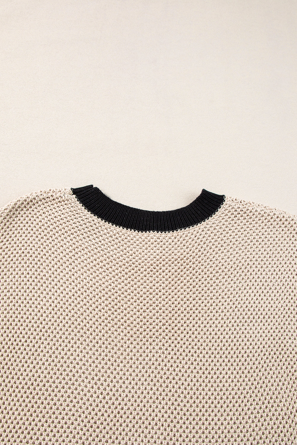 Beige knit top with black contrast trim neckline and cap sleeves.