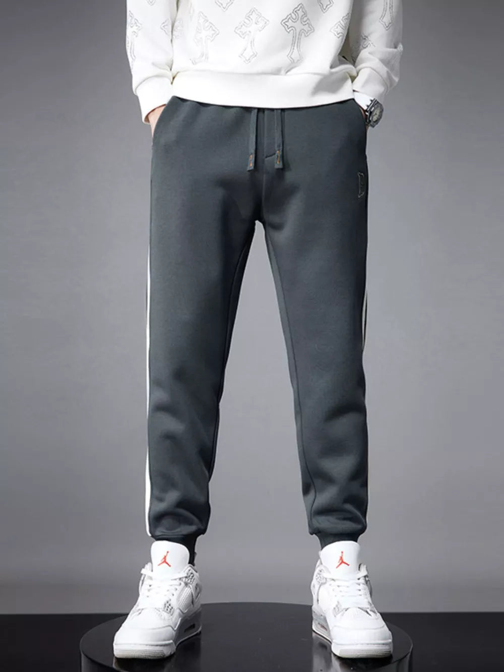 Dark gray cotton joggers for men with white side stripes and cuffed ankles.