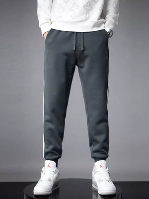 Dark gray cotton joggers for men with white side stripes and cuffed ankles.