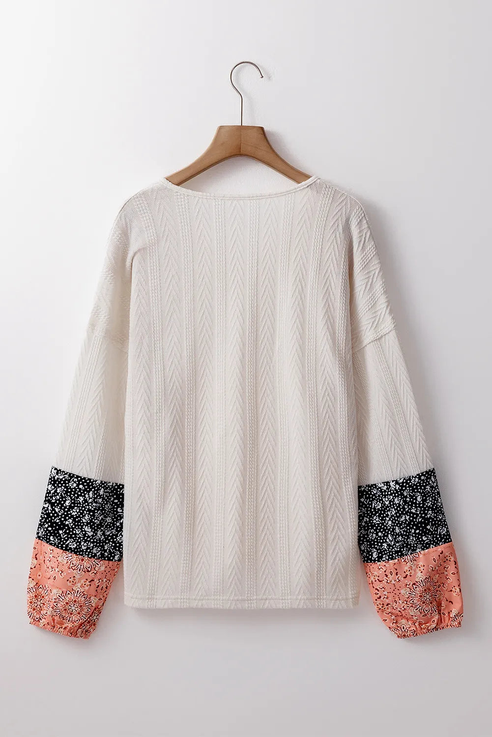 Textured sleeve henley blouse in cream with patterned cuffs in black and dusty pink.