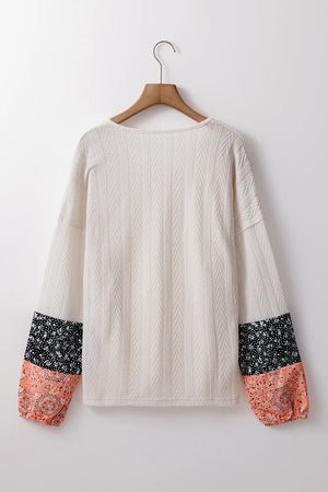 Textured sleeve henley blouse in cream with patterned cuffs in black and dusty pink.