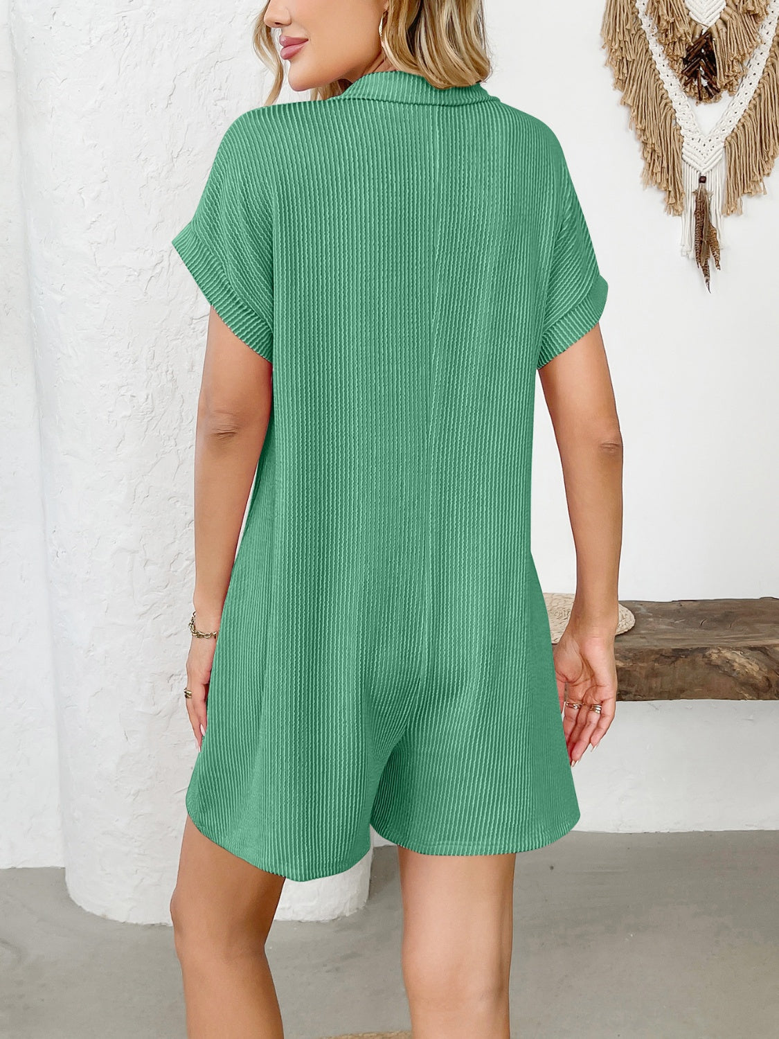 Green ribbed knit romper with short sleeves, collar, and patch pockets.