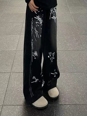 Men's black wide-leg jeans with white graffiti print and heart details.