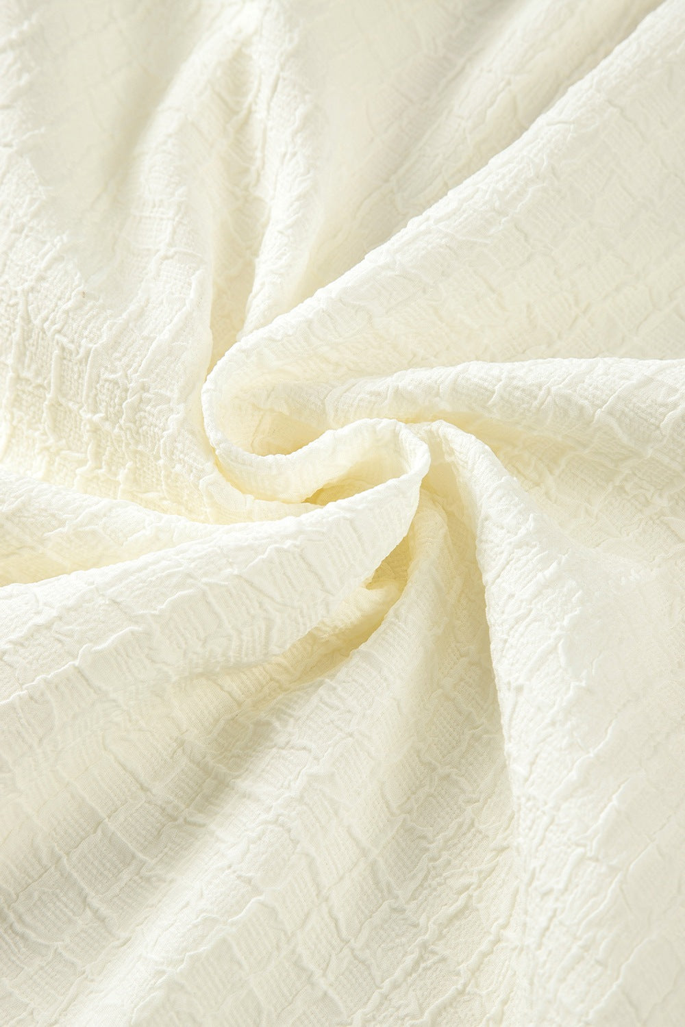 Beige voluminous blouse with textured fabric and embroidered sleeves.
