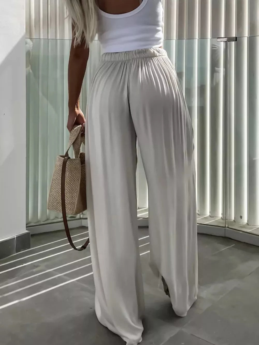 Maternity pants in apricot with paperbag waist and wide legs, styled with a white tank and straw bag.