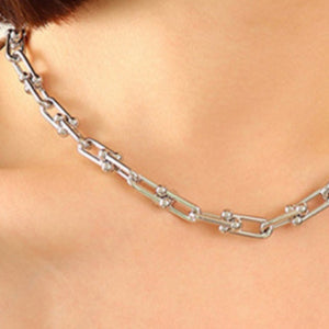 Chunky silver chain collar necklace with bold links and small bead details.