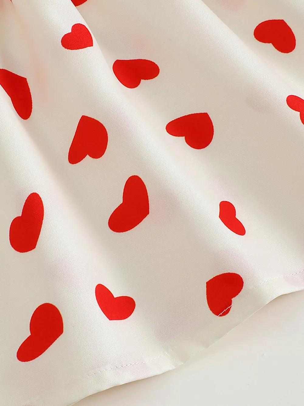 Baby dress with red heart print on white cotton fabric
