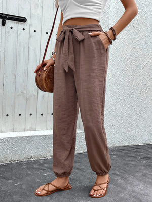 Brown textured tie-waist jogger trousers with elasticated cuffs and pockets.