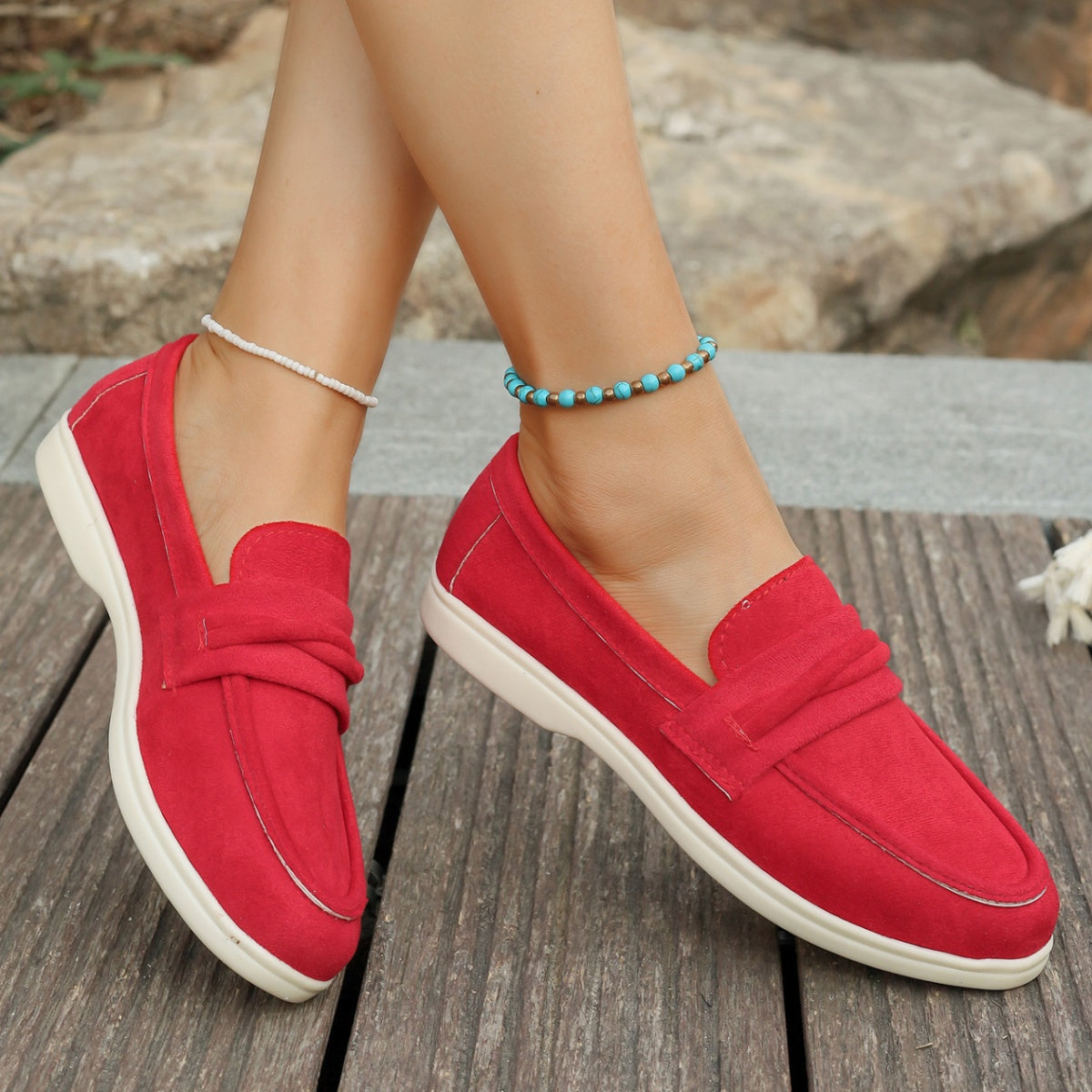 Red slip-on loafers with round toe and decorative knot detail.
