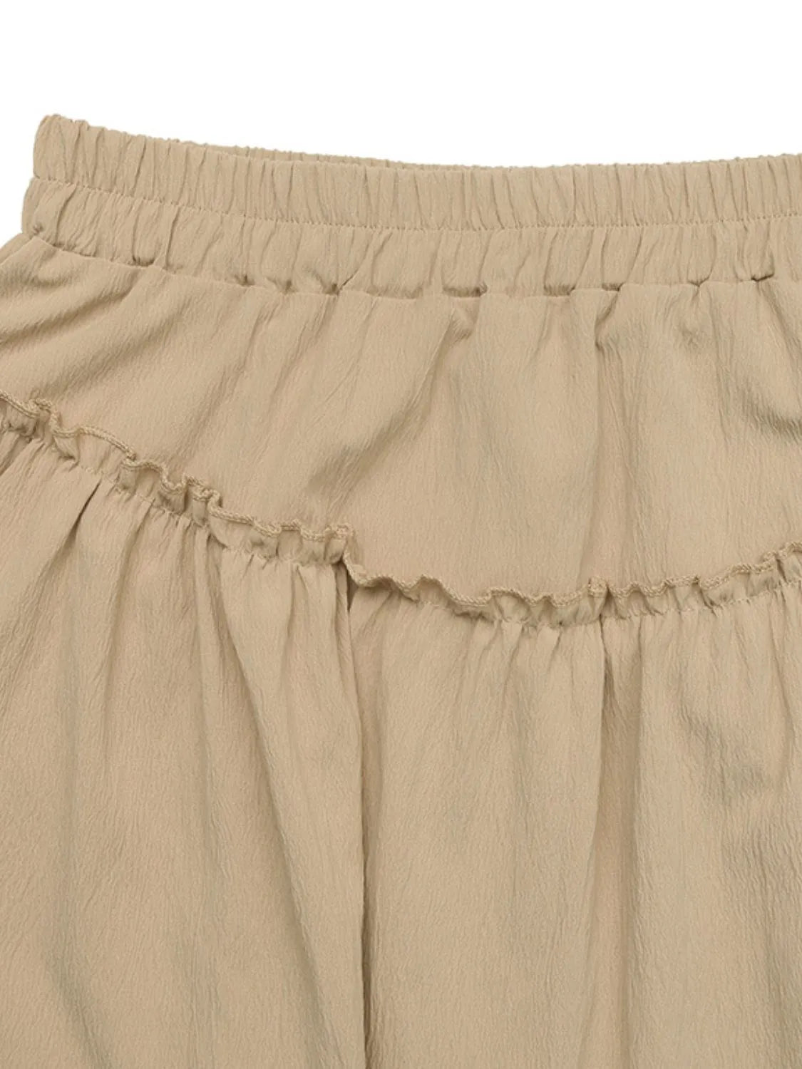 Tiered ruffle mini skirt in tan with elastic waistband and textured fabric.