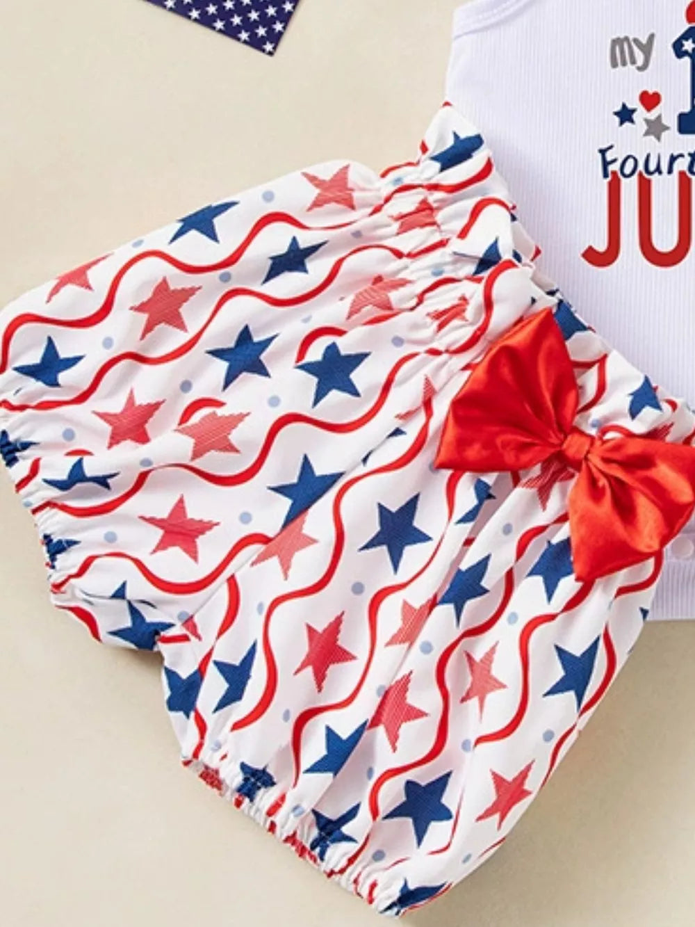 Patriotic baby bloomer shorts with red bow, white bodysuit with "my 1st Fourth" text.