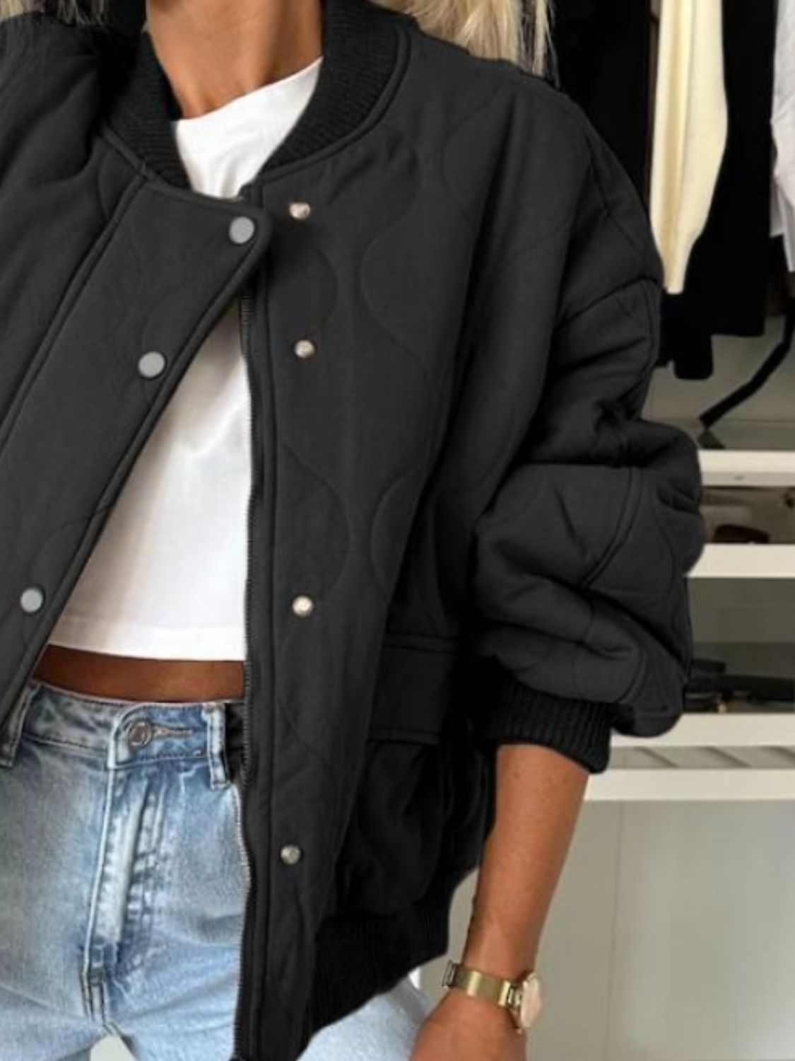 Black quilted bomber jacket with rounded sleeves and snap front closure.