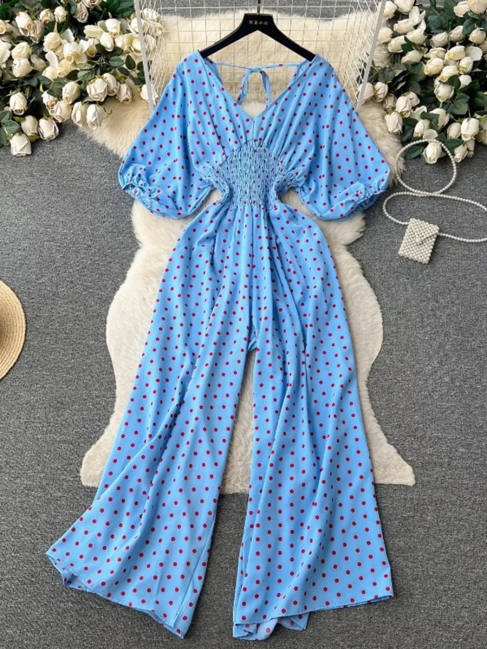 Light Blue polka dot smocked wide-leg romper with V-neck and tie back.