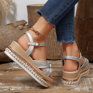 Silver bow knot wedge sandals with braided trim and ankle buckle, styled with jeans.