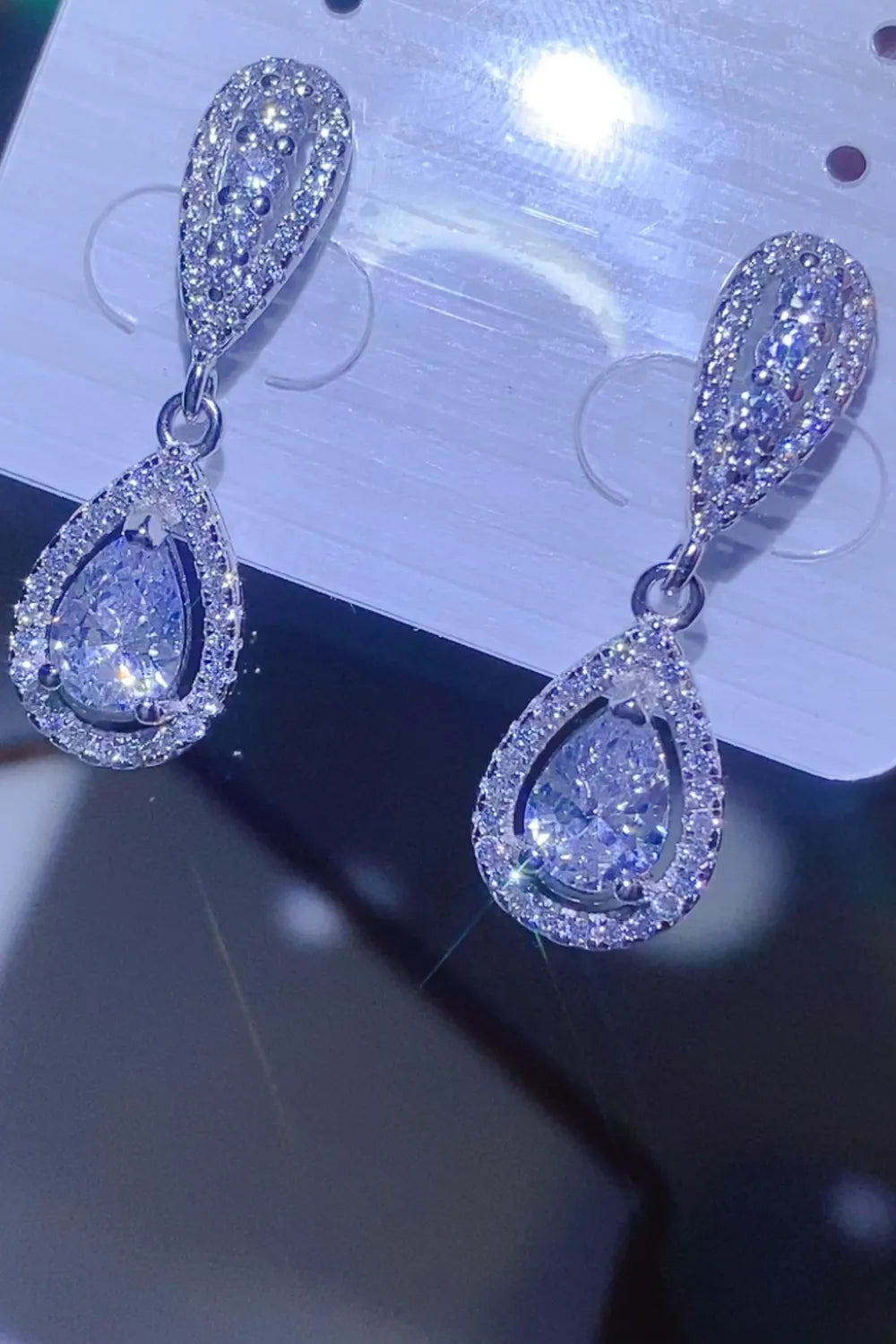Silver moissanite drop earrings with pavé halo detail and pear-shaped center stone.