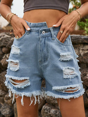 Distressed denim cutoff shorts in dusty blue with an asymmetric waist and frayed hem.