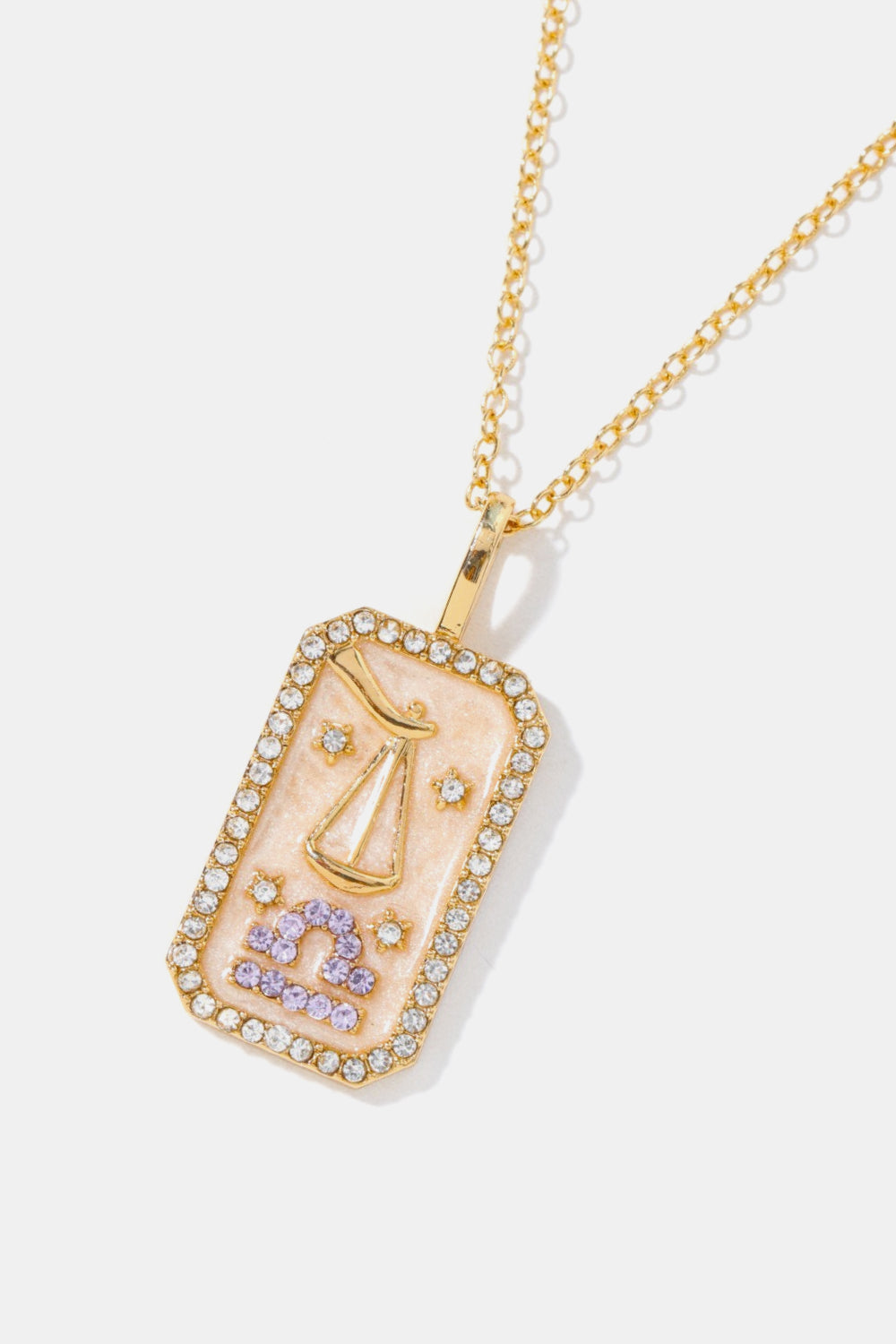 Libra zodiac sign crystal pendant necklace with 14K gold plating and rhinestone border.