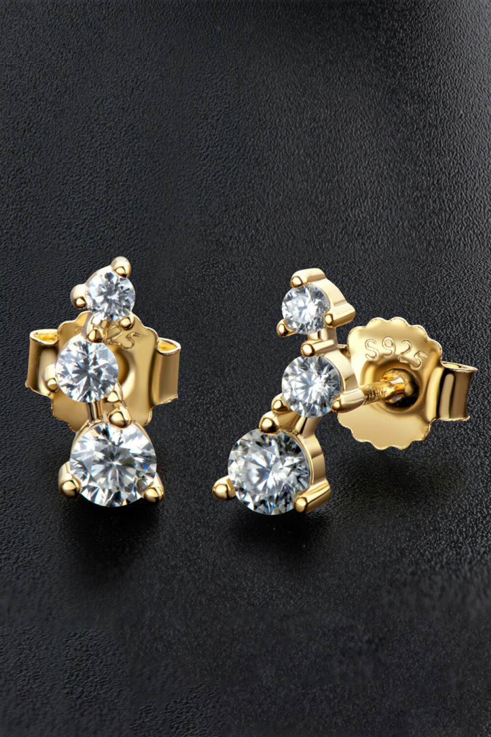 Gold moissanite cluster stud earrings with three round-cut stones each.