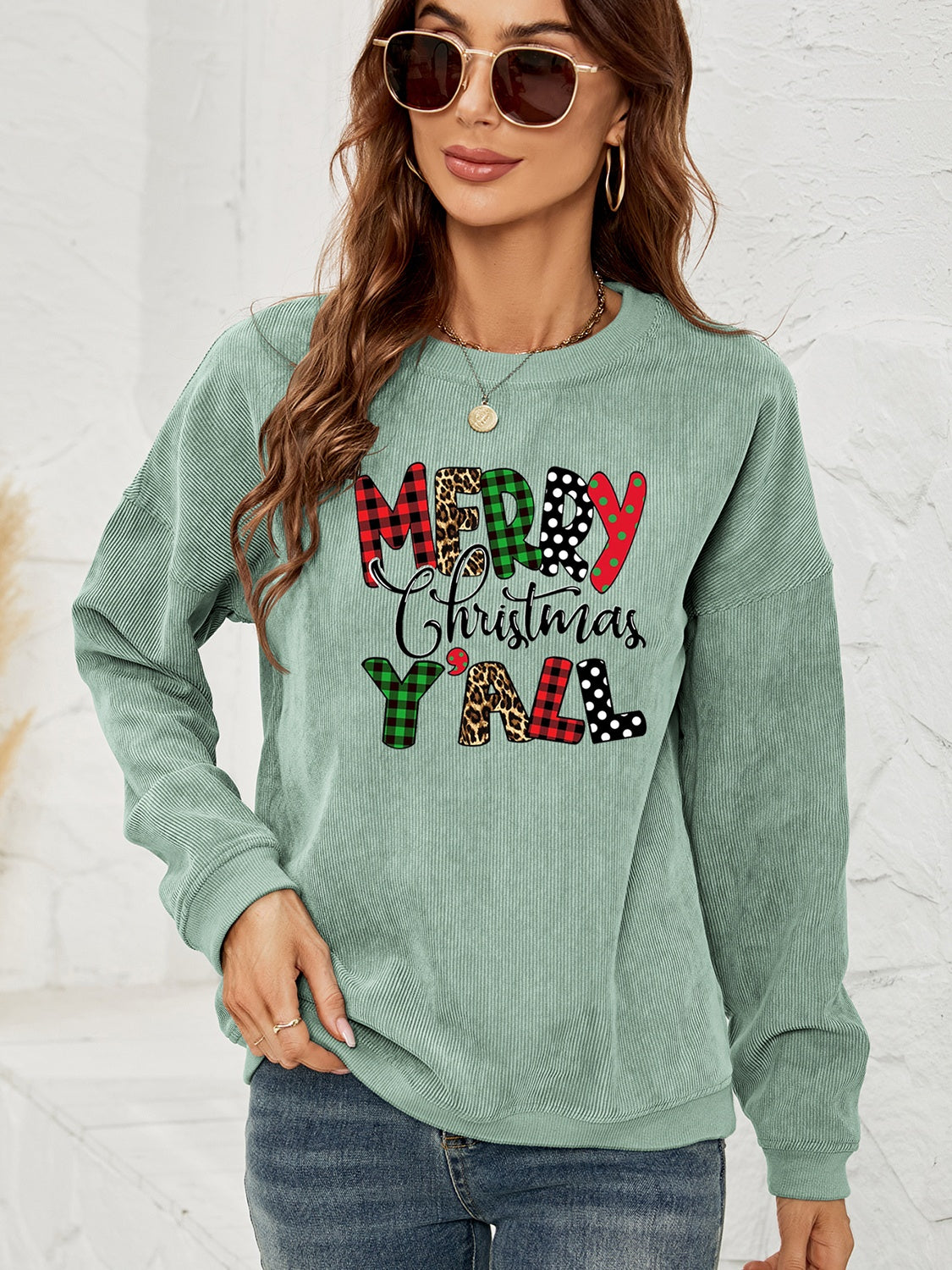 Sage corduroy sweatshirt with Merry Christmas Y'all graphic in buffalo plaid, leopard, and polka dot patterns.