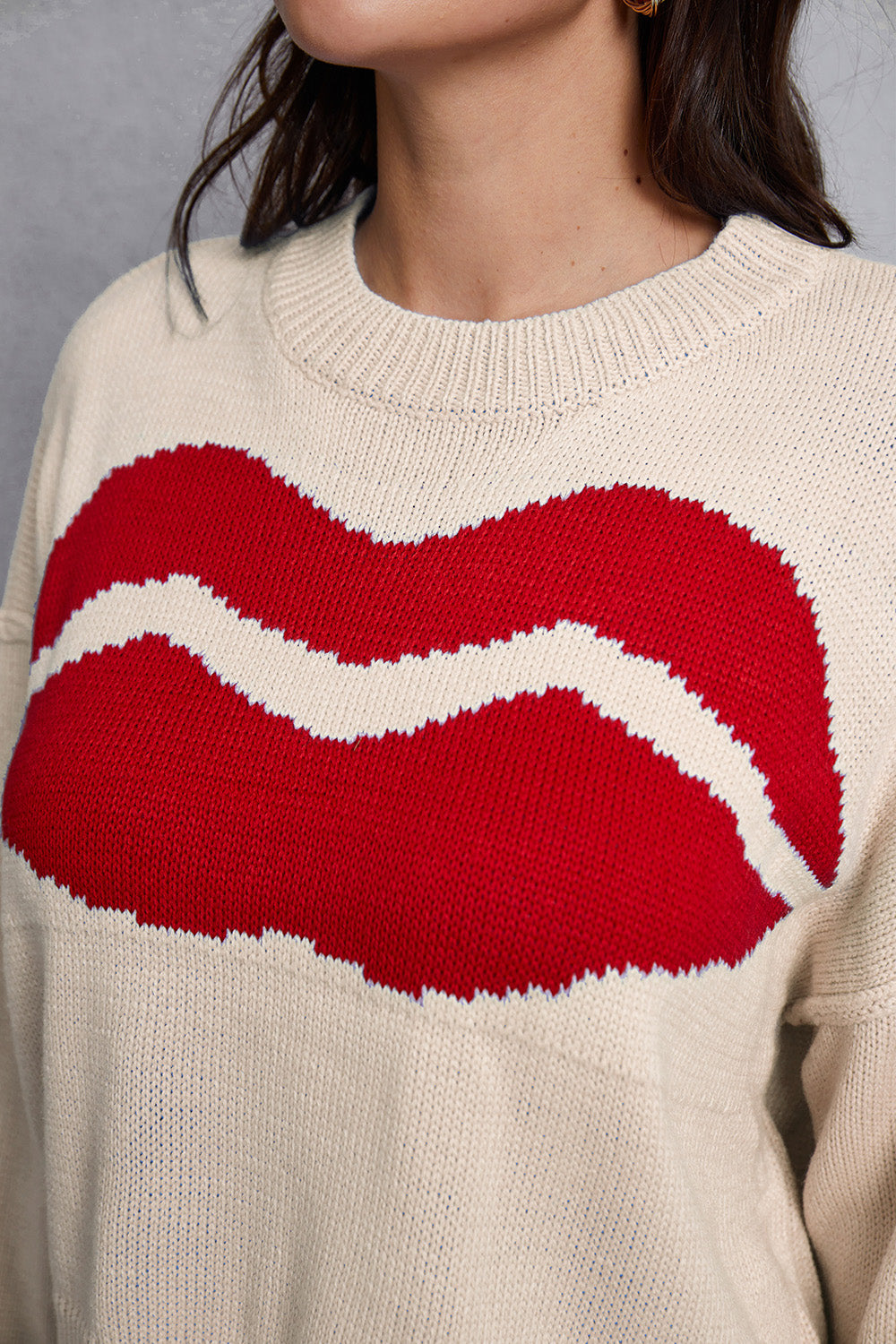 Cream knit sweater with large red lips graphic and distressed hem detail.