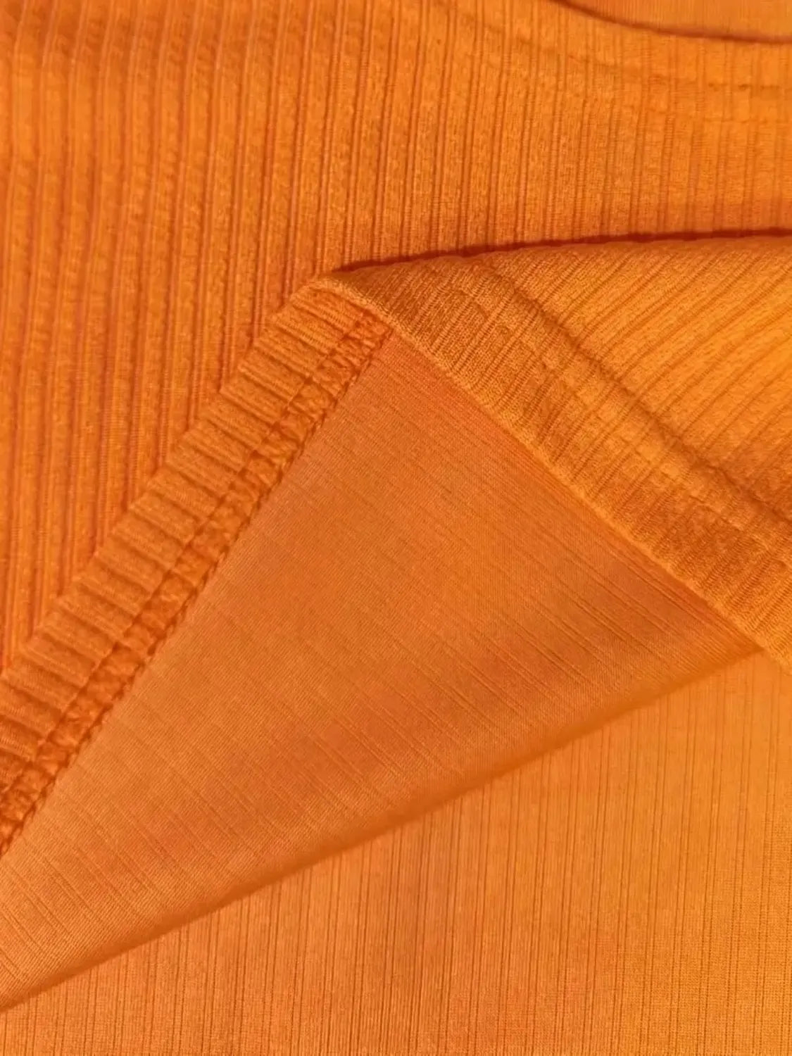 Orange ribbed knit crop top detail showing texture and seam.