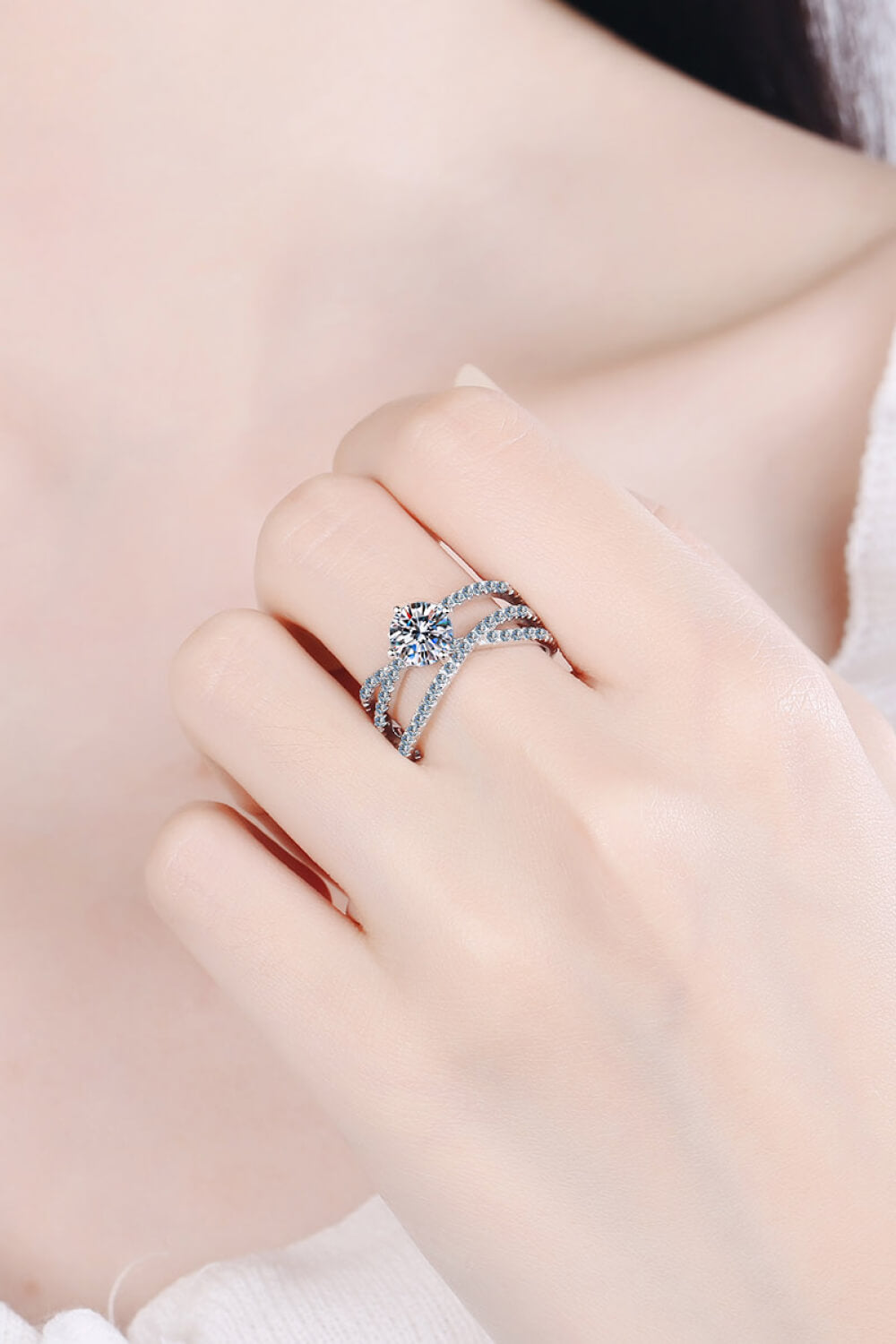 Silver pavé-set crossover engagement ring with a round-cut center stone.