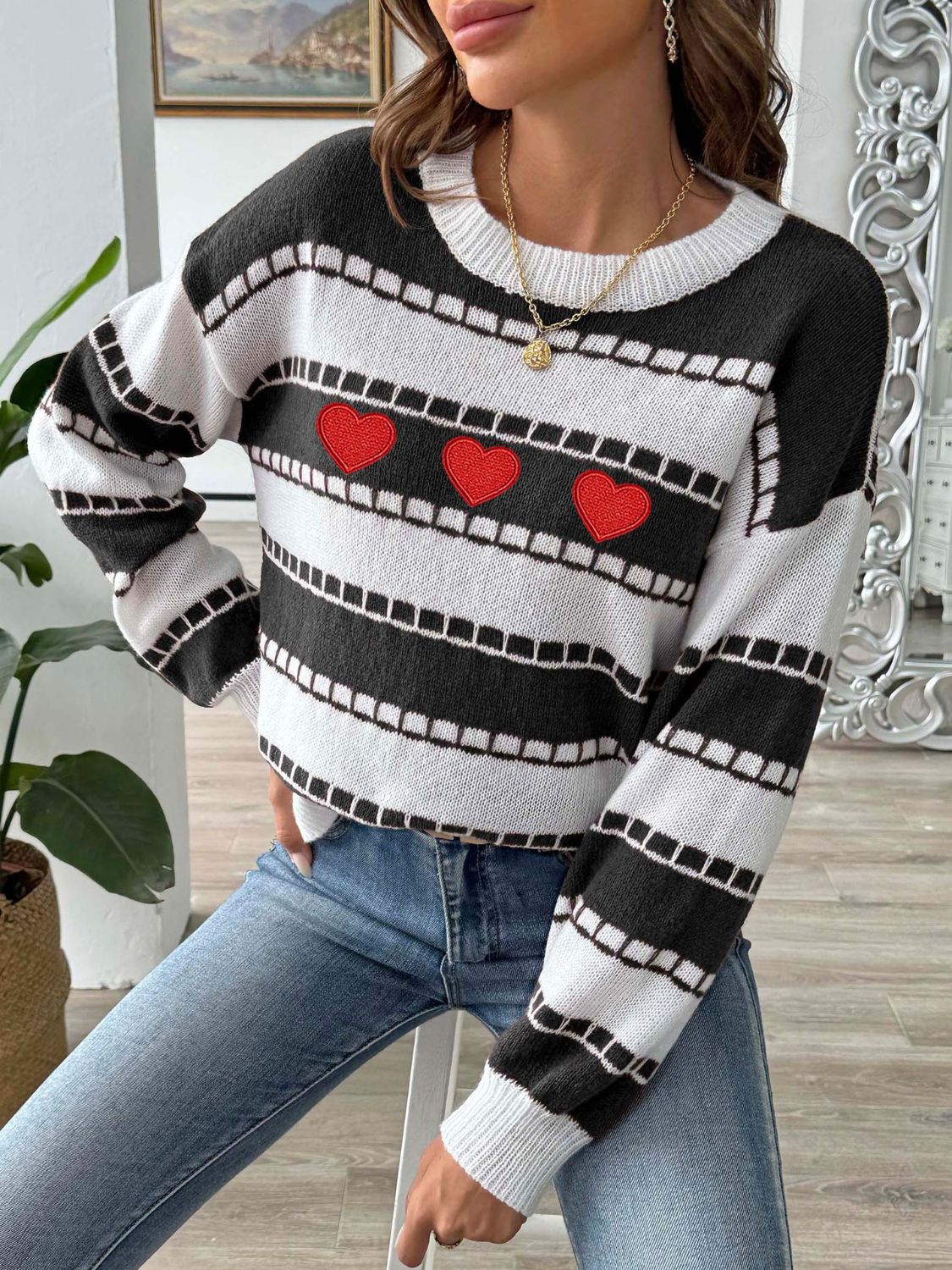 Black and white striped knit sweater with embroidered red hearts and a crew neck.