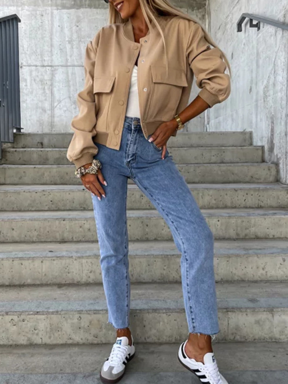 Camel faux leather bomber jacket with sculpted sleeves and flap pockets, styled with jeans.