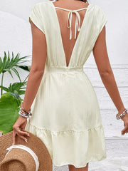 Tiered cap sleeve mini dress in pale yellow with a deep V-back and tie detail.