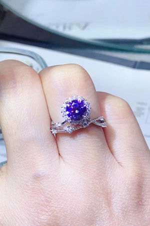 Purple halo moissanite engagement ring set with diamond accents on a twisted band.