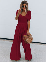 Burgundy textured wide-leg jumpsuit with subtle waist and short sleeves.