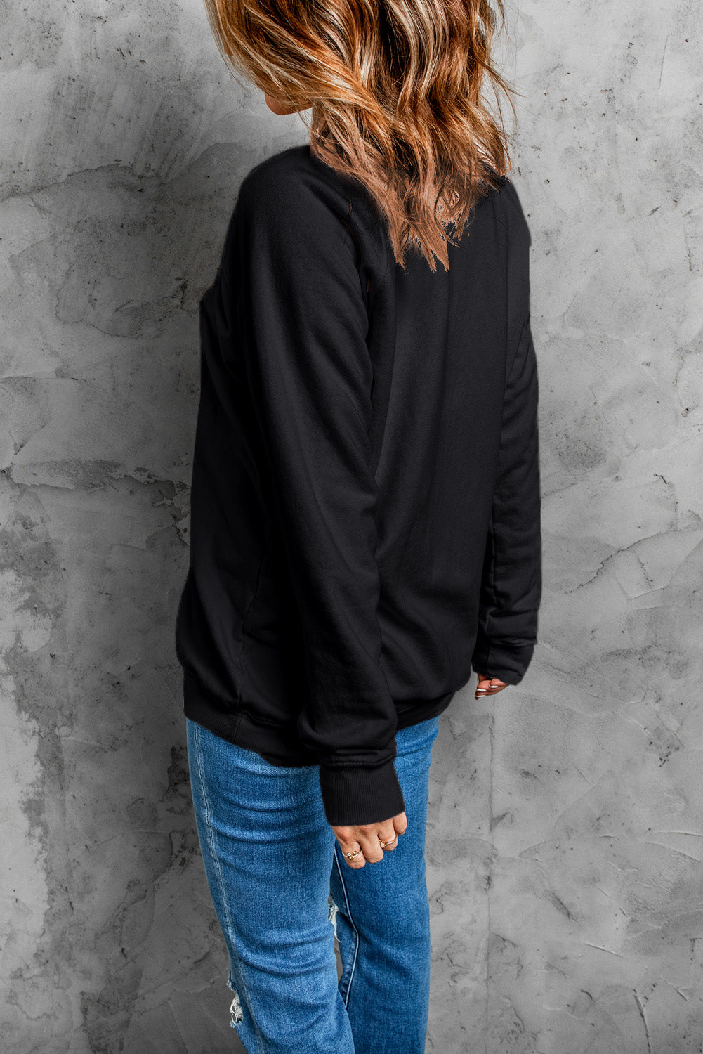 Black crewneck sweatshirt with embroidered pumpkin patch detail, long sleeves, and ribbed cuffs.