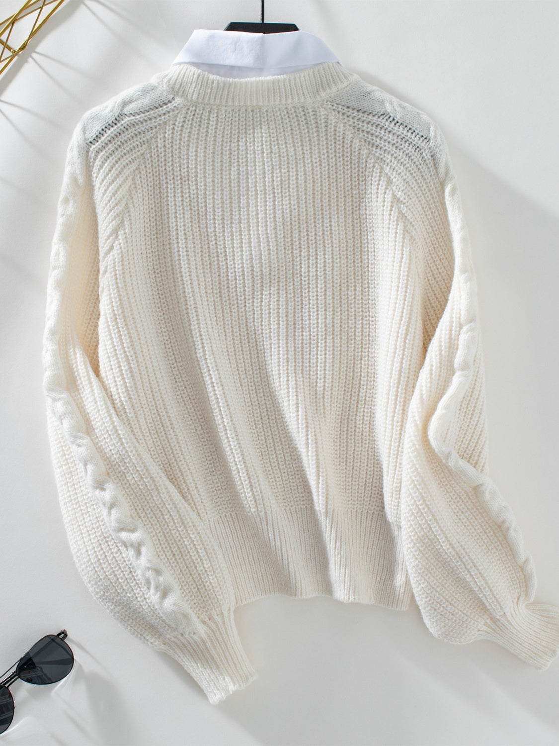 Cream cable knit sweater with blouson sleeves and V-neck detail.