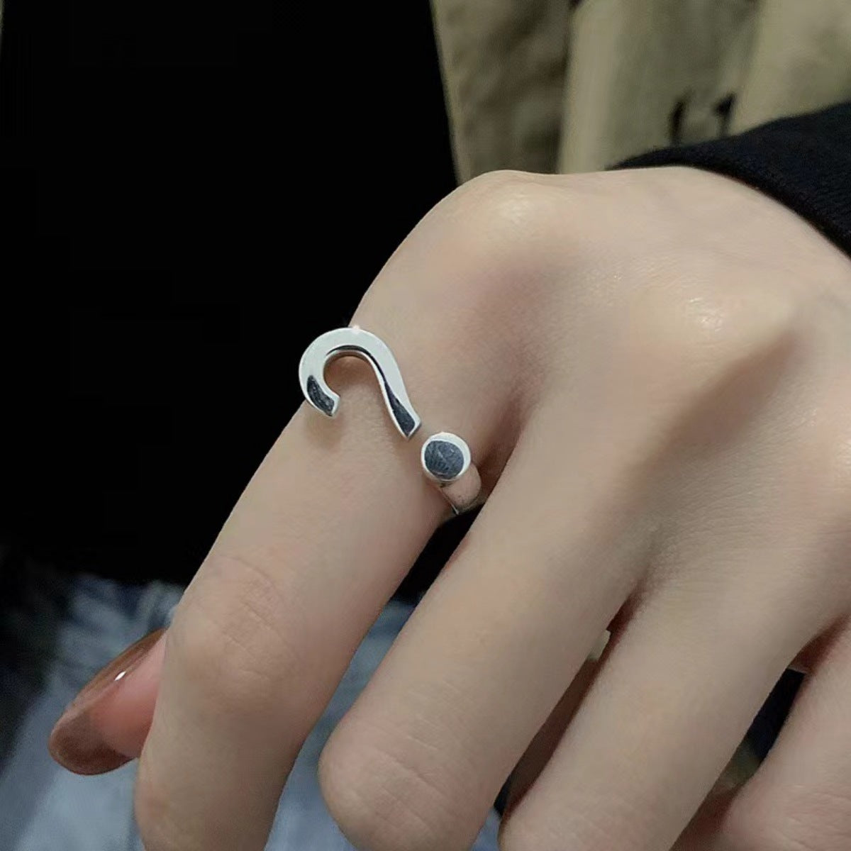 Sterling silver open ring with question mark detail on a finger