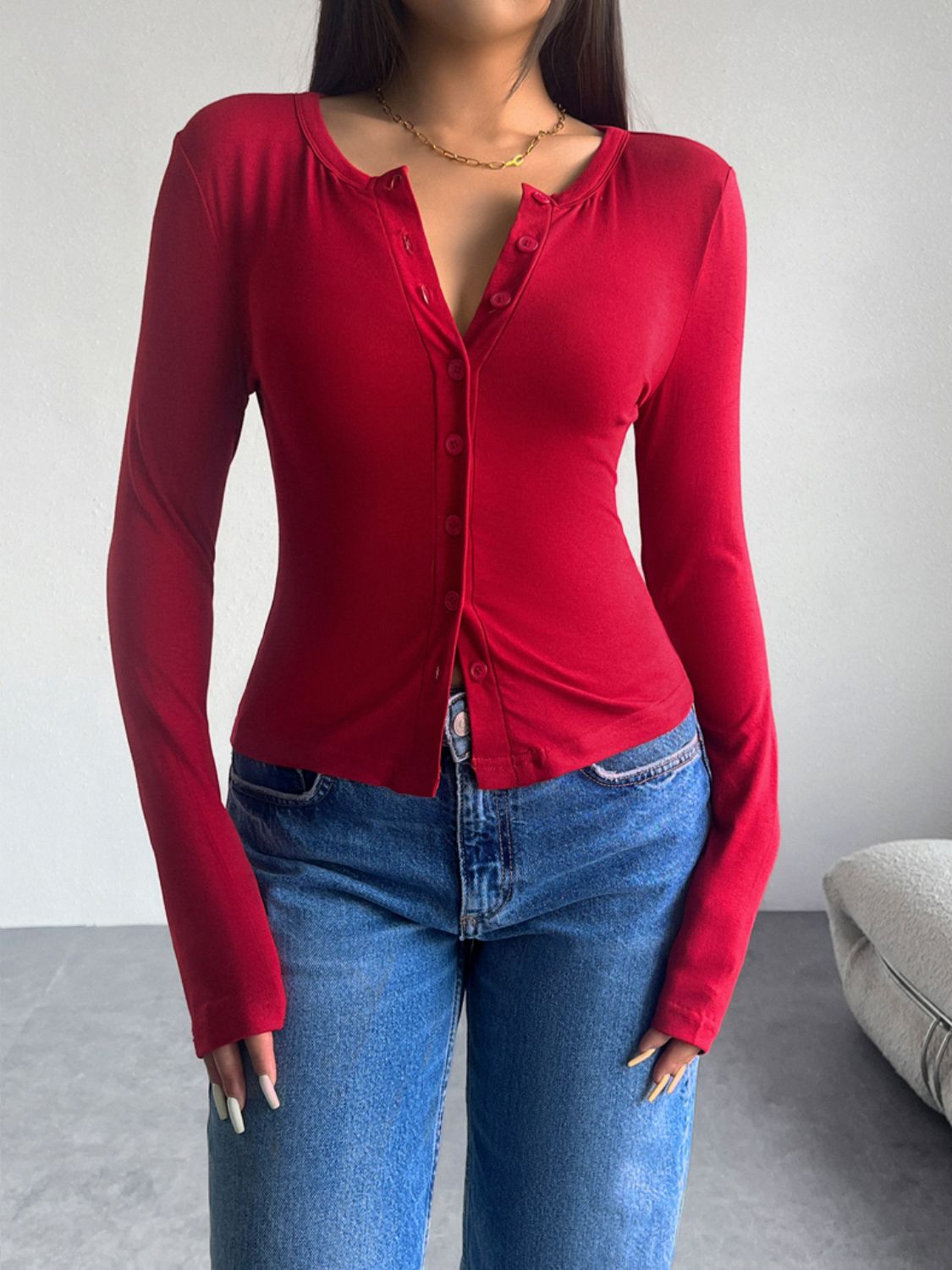 Scarlet button-up cardigan with a scoop neckline and long sleeves, styled with jeans.