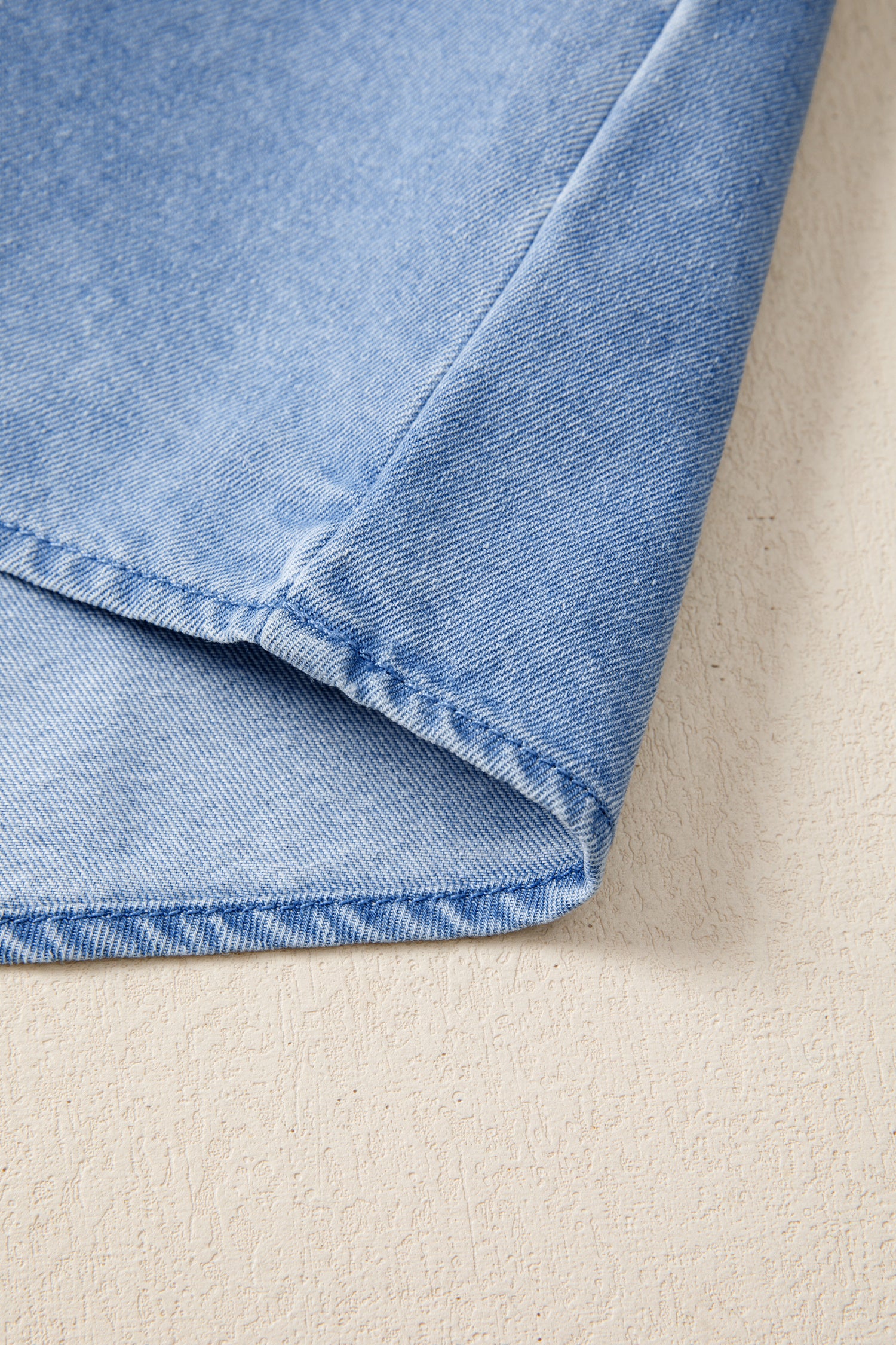 Light blue distressed denim top with visible stitching detail