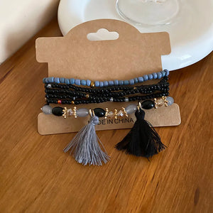 Beaded tassel stacked bracelet set with blue, black, and grey beads.