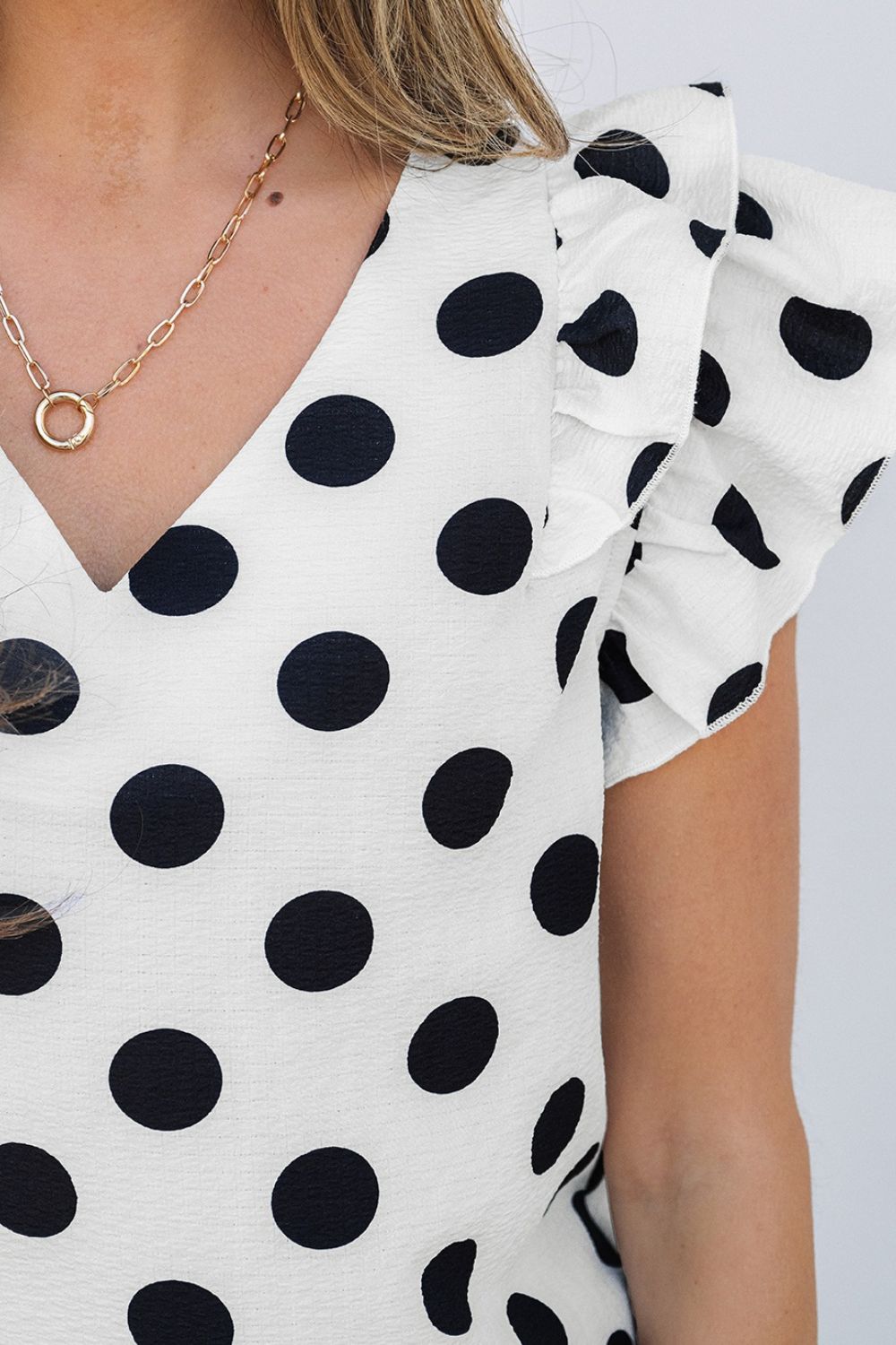 Polka dot blouse with V-neck and flutter sleeves.