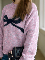 Pink intarsia knit sweater with black bow detail, crew neck, long sleeves, acrylic blend.