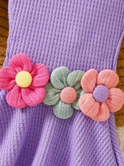 Purple cotton jumpsuit with smocked bodice and floral applique detail.