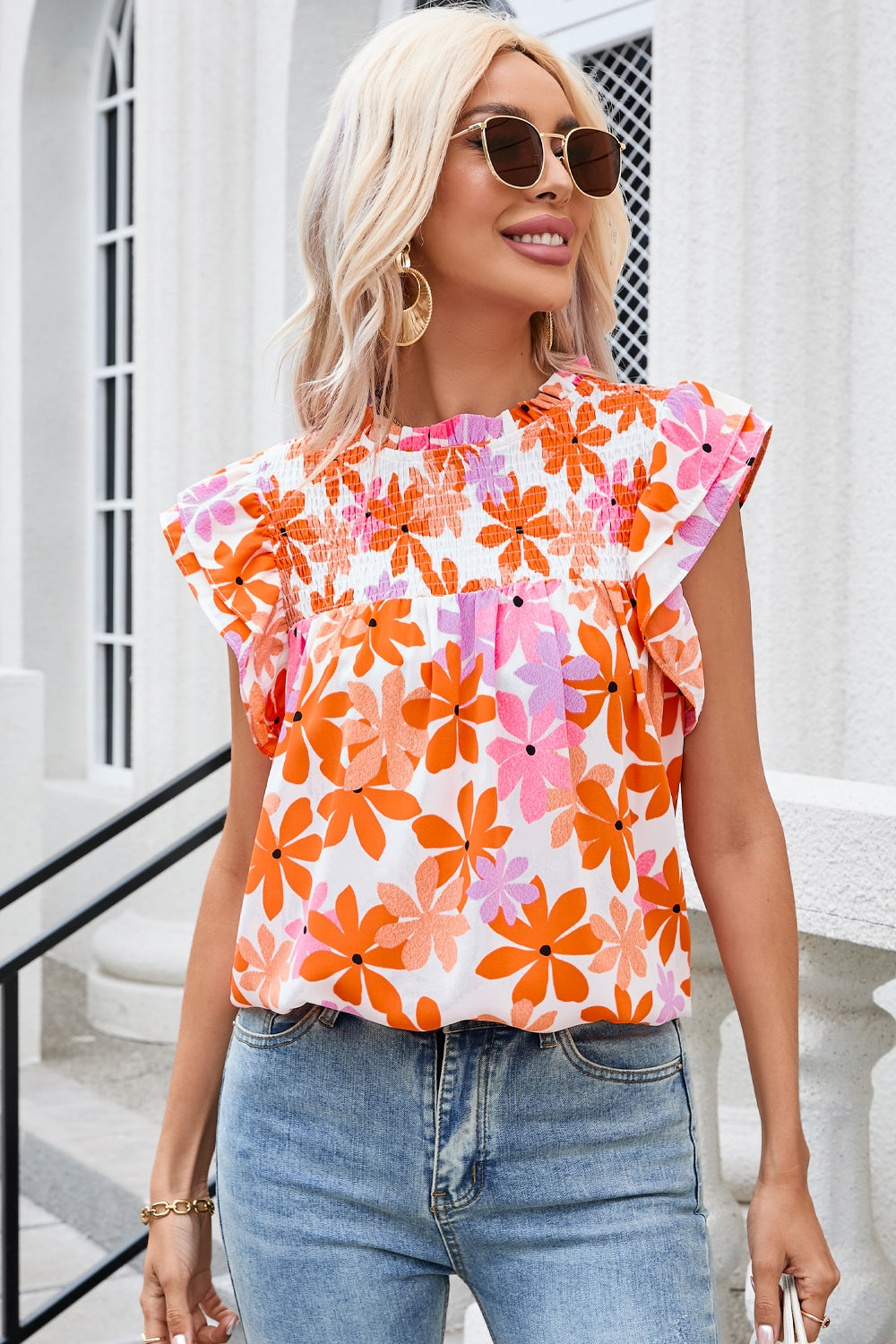 Multicolor floral smocked bodice flutter sleeve blouse with ruffled neckline.