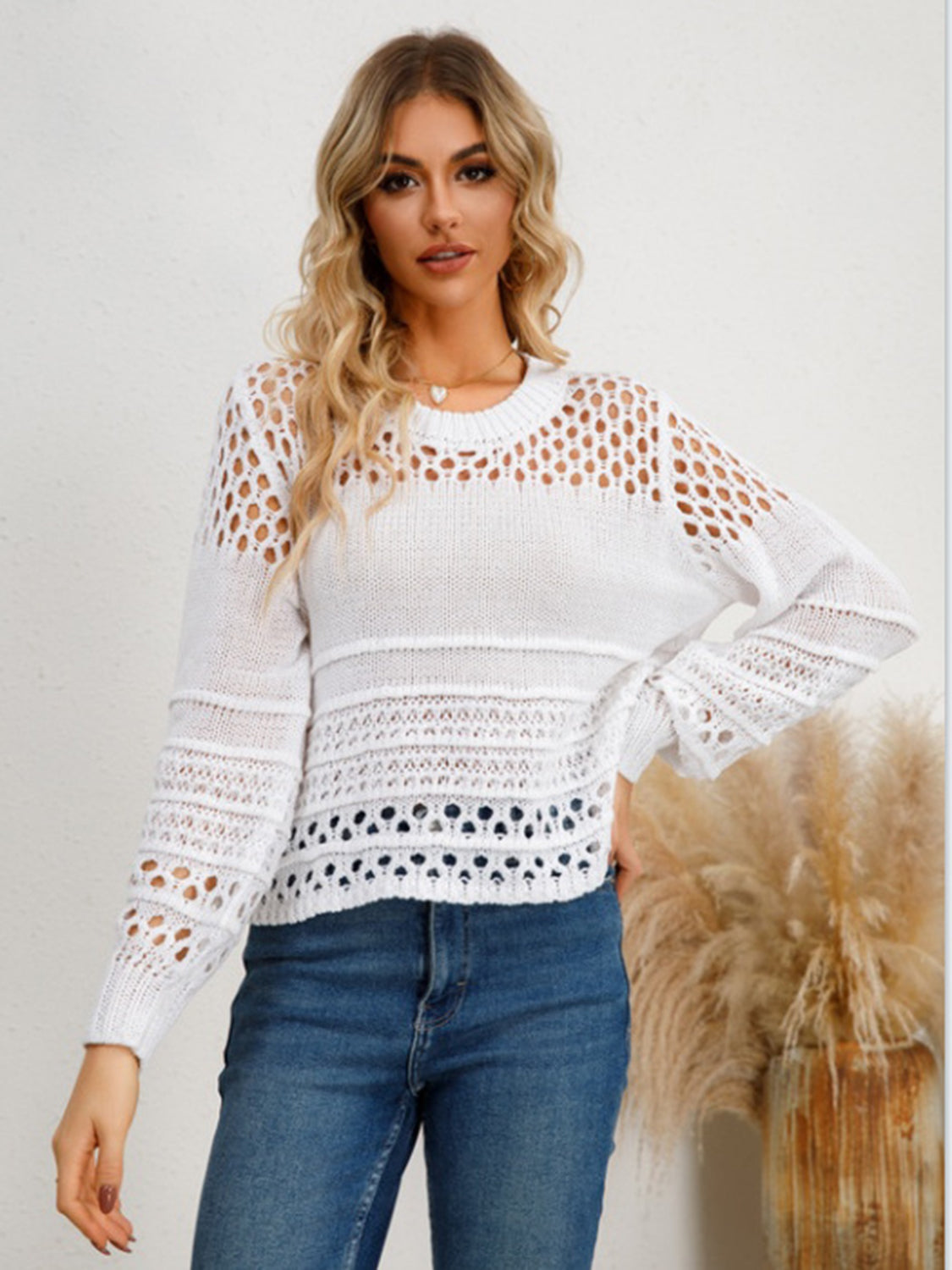 White openwork knit sweater with crew neck and long sleeves, featuring intricate stitch details.
