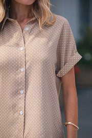 Chic polka dot button-up blouse with cuffed short sleeves and a collared neckline.