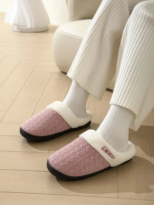 Dusty pink cable knit house slippers with shearling lining and a decorative button detail.