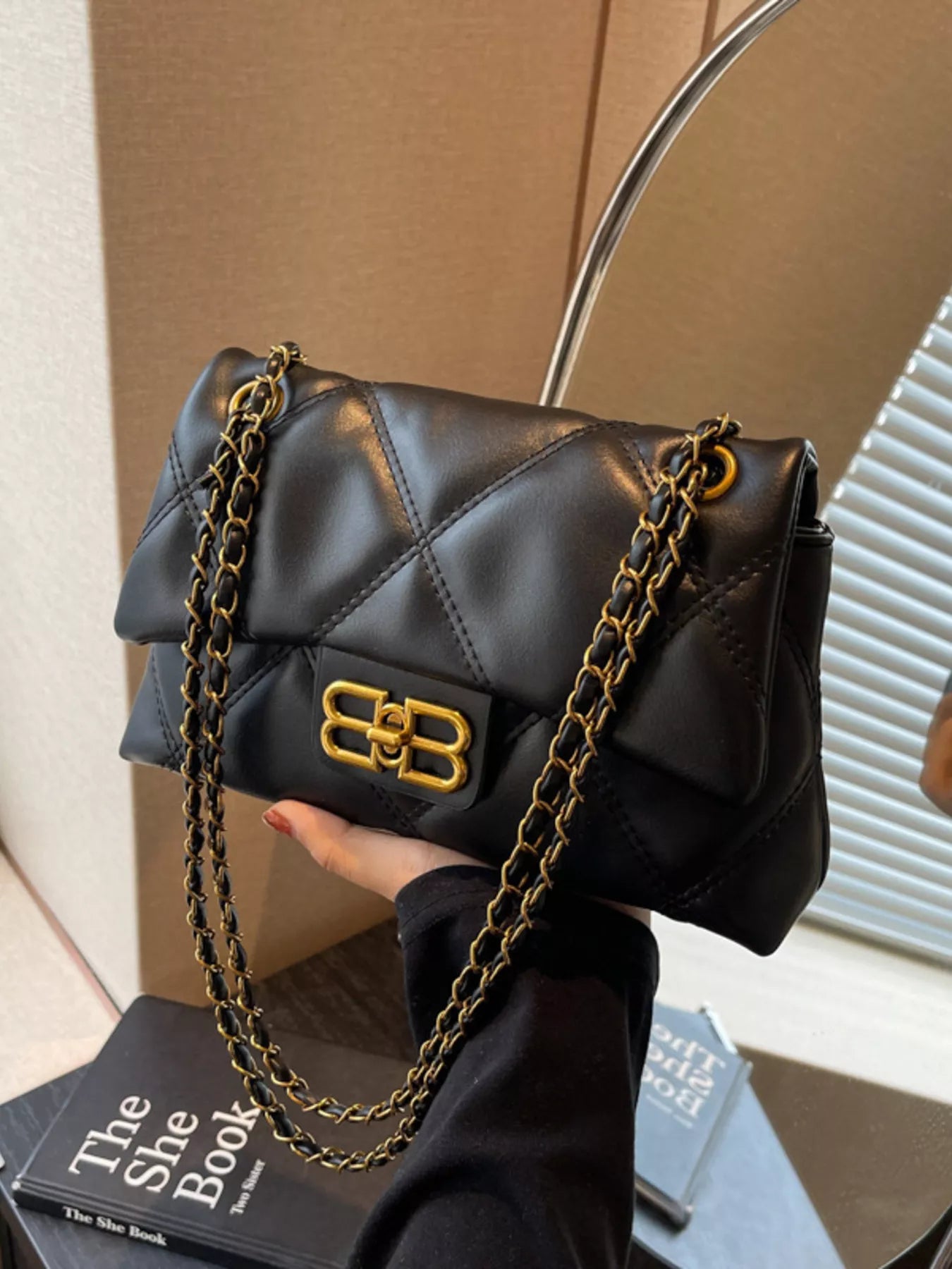Black quilted flap chain shoulder bag with gold hardware and logo clasp