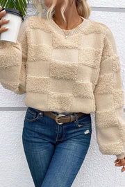 Beige textured checkerboard knit sweater with crew neck and long sleeves.