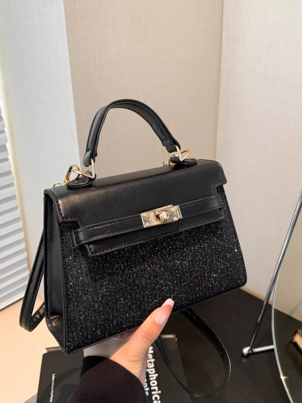 Black glitter textured mini crossbody bag with gold hardware and top handle.